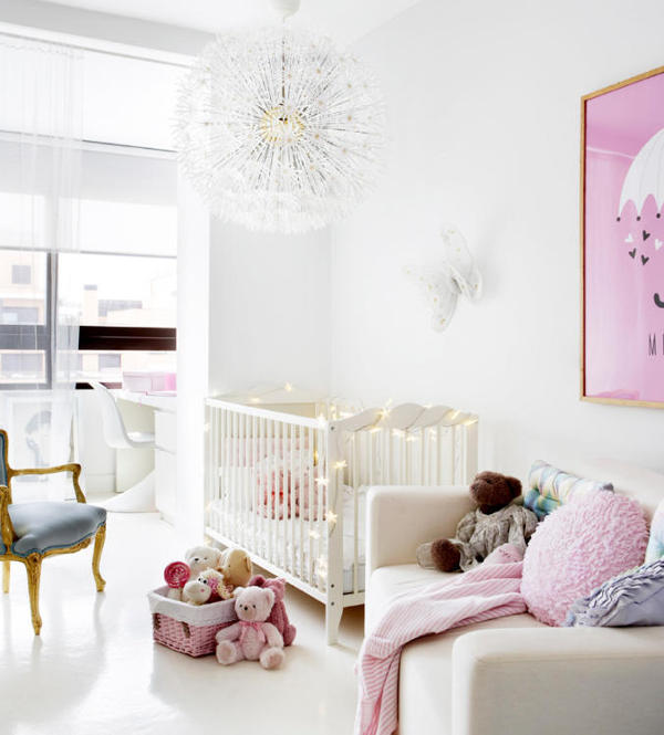The kid's room is done in white and pink, with a cute lamp and a couple of refined touches