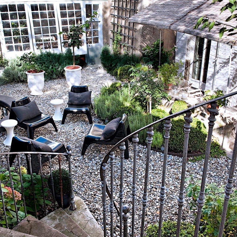 The small garden looks like a heaven with herbs and lavender in antique pots and modern black chairs