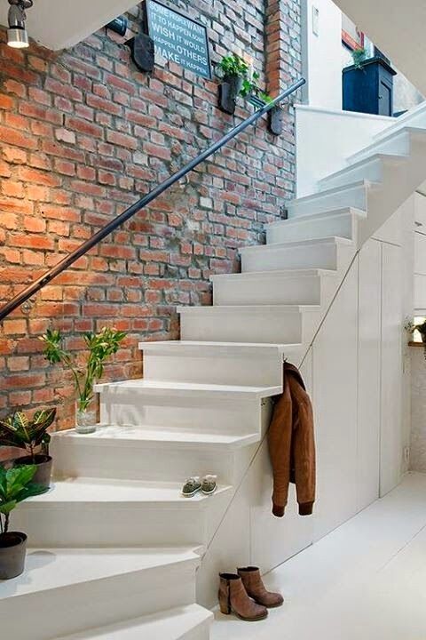 exposed brick wall above the stairs gives a style to this entryway