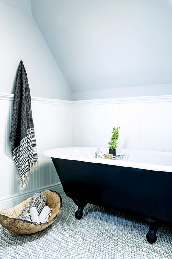 simple bathroom with penny tile floors and a black clawfoot tub