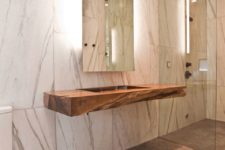 13 a stone slab and a rough wood countertop highlighted with lights behind the mirror
