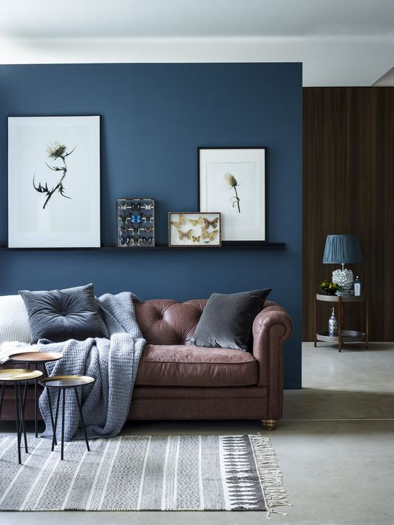 chic seating area with a brown sofa and a navy accent wall and textiles