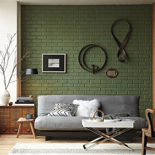 sage green brick wall and a grey sofa