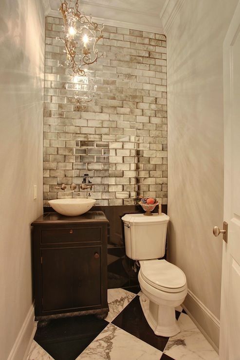 mirrored subway tiles create a bold accent and reflect the light making the small powder room bigger