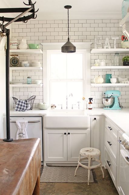 a white modern farmhouse kitchen with white subway tiles on the wall and open shelves plus pendant lamps is a cool and lovely space