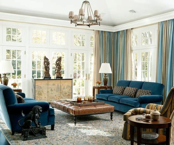 navy blue upholstery, blue and beige draperies, beige room decor and a rich brown leather ottoman