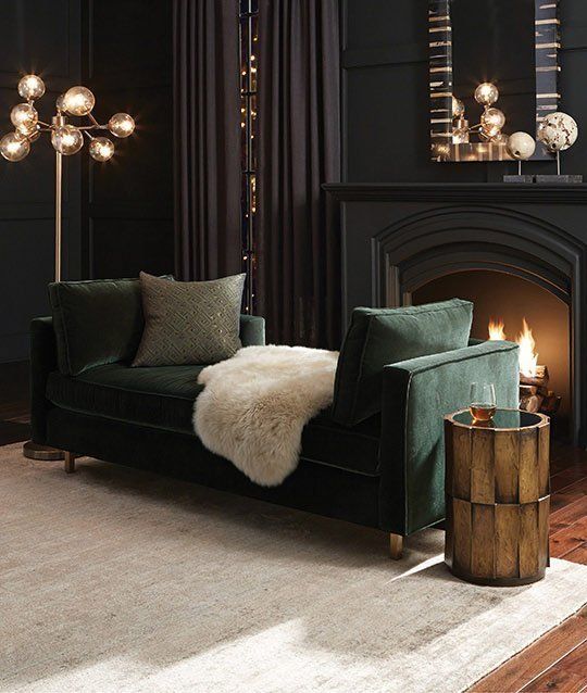 soft black living room with a dark green sofa, art deco lights and a working fireplace