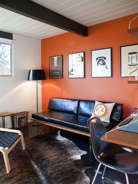 an orange accent wall makes this mid-century space vivacious