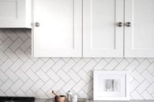 a kitchen backsplash clad in subway tiles with a diagonal herringbone pattern is a cool way to add interest to your space without adding color