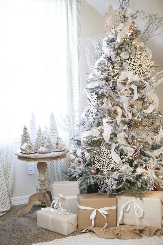 white Christmas tree with lots of ornaments - oversized snowflakes, pinecones and a chic ribbon garland