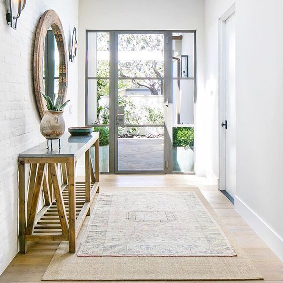 beautiful rustic entry with steel-frame doors, a round reclaimed wood mirror, a white brick wall
