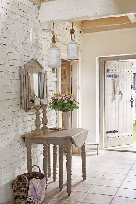shabby chic entryway with a whitewashed brick wall and wooden table and candle holders