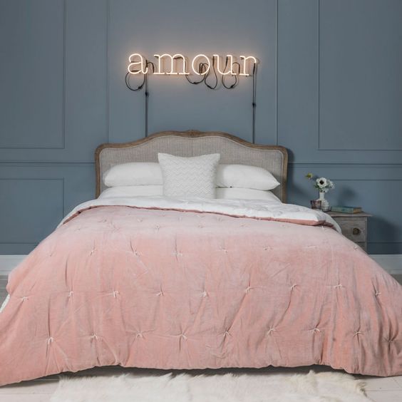 pink velvet bed throw and a cool light sign create a mood