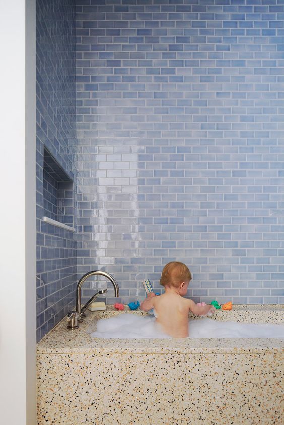 unusual watery blue subway tiles and a terrazzo covered bath look so contrasting and cool together and make your bathing space unique