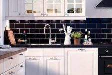 navy subway tiles and black countertops make white cabinetry stand out and create a contrast