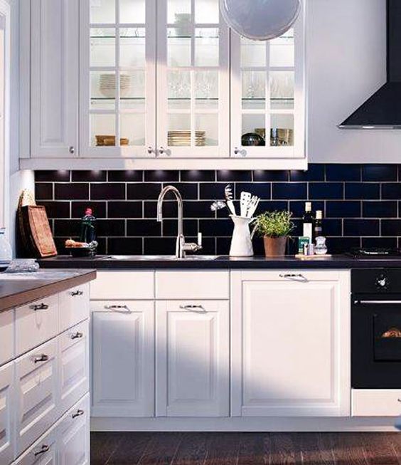 navy subway tiles and black countertops make white cabinetry stand out and create a contrast