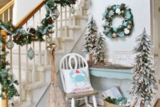 29 coastal Christmas entryway decor in pale blue, with a garland, a wreath, some trees and ornaments