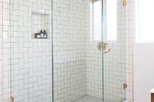 white subway tiles in the shower clad in a creative herringbone pattern create a bold space without adding color and look cohesive with penny tiles on the floor