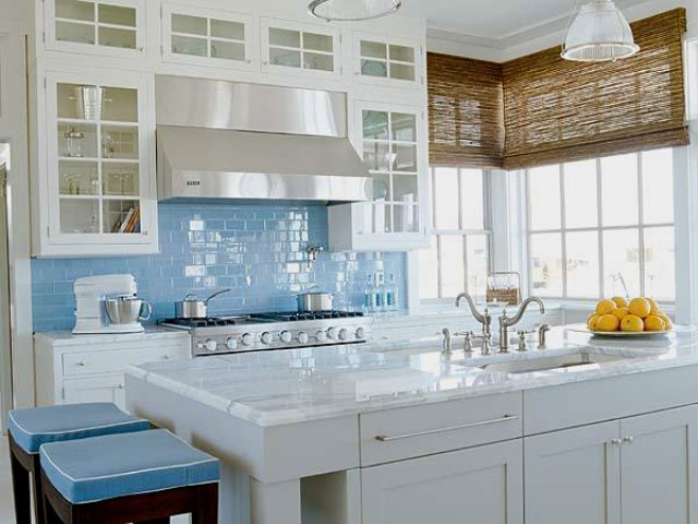 light blue subway tiles add a coastal feel tothe kitchen, and blue stools support this color