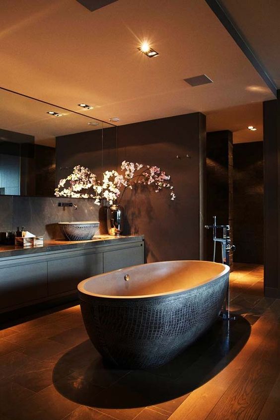 Spacious dark bathroom, a free standing bathtub with a textural look