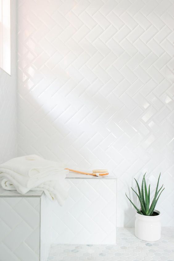 simple subway tiles with white grout in a herringbone pattern in the shower create a chic all-neutral look that is seamless and cool