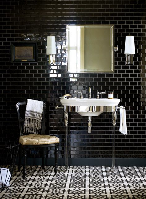 a moody vintage bathroom clad with black subway tiles, with with a vintage sink and a mirror cabinet plus a chair for a chic look