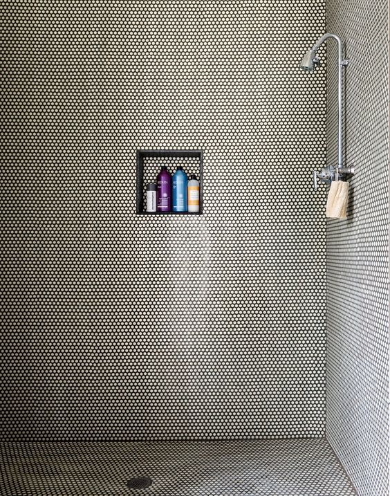 white penny tiles with black grout adds texture to the shower space
