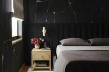a beautiful and chic moody bedroom with catchy wallpaper, a black bed with an extended headboard, grey bedding, neutral nightstands