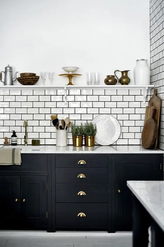 a bold black kitchen with a white subway tile backsplash accented with black grout and touches of gold and brass