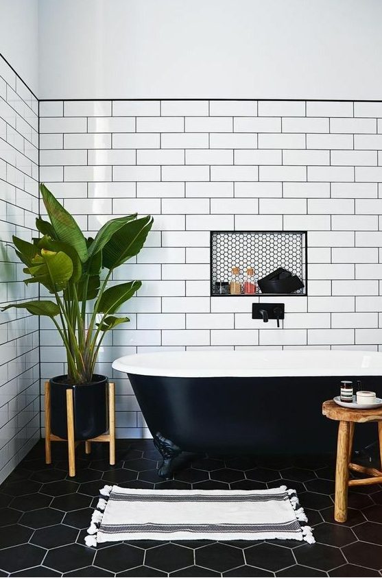 A chic bathroom with a black retro free standing bathtub that matches the space perfectly