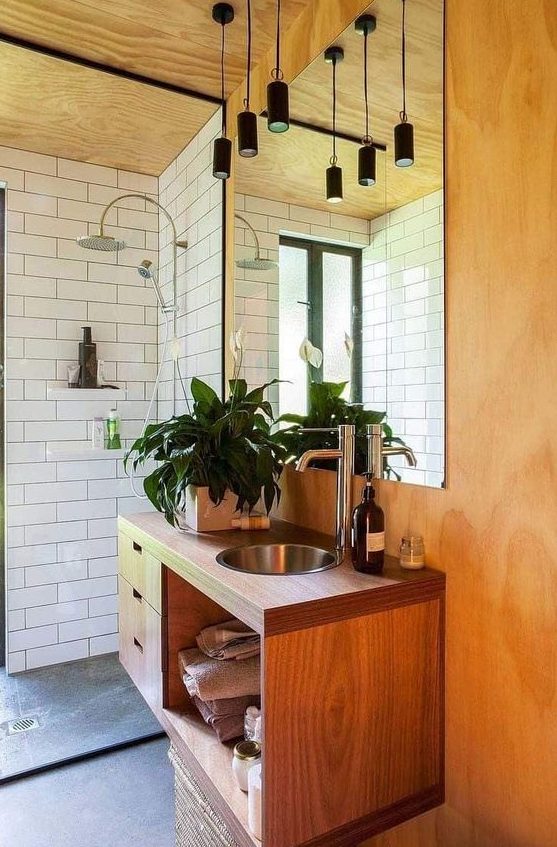 a chic mid-century modern space with white subway tiles, lots of plywood and wood, black pendant lamps over the sink