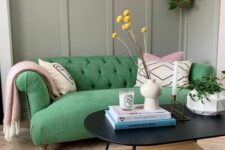 a cool living room with grey paneling, a bold green sofa with graphic pillows, a tiered coffee table and some plants