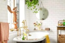 a fancy and whimsy bathroom with a gorgeous printed tile floor, a black vintage tub, a crystal chandelier and vintage furniture and a potted plant