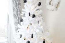 a lovely white Christmas tree decorated with black baubles and little Christmas trees, with gold bells and lights is amazing
