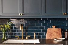 a matte navy kitchen with navy subway tiles and gold touches for a bold and dramatic kitchen in dark shades