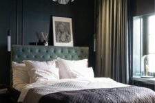 a moody bedroom with black walls and a ceiling, a green upholstered bed, neutral bedding, a catchy pendant lamp and chic curtains