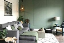 a neutral living room with a green accent wall, a grey sectional with green textiles, potted greenery and some lovely decor