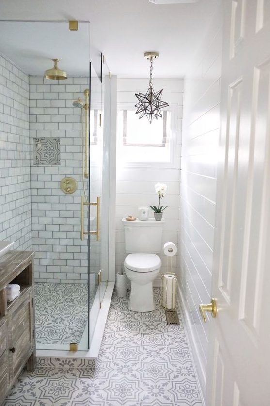 a neutral small bathroom with beadboard, printed tiles, subway tiles in the shower, gold touches and a star-shaped chandelier