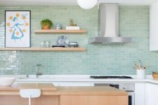 a pretty modern kitchen with white cabinets and a stained kitchen island, a green subway tile wall and open shelves