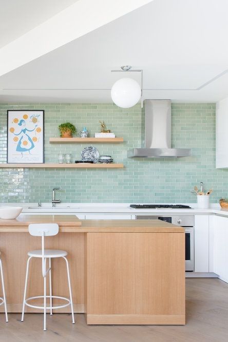 a pretty modern kitchen with white cabinets and a stained kitchen island, a green subway tile wall and open shelves