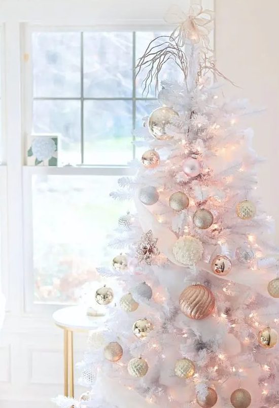 a pure white Christmas tree with gold, white and peachy pink ornaments and lights plus a bow tie and some twigs