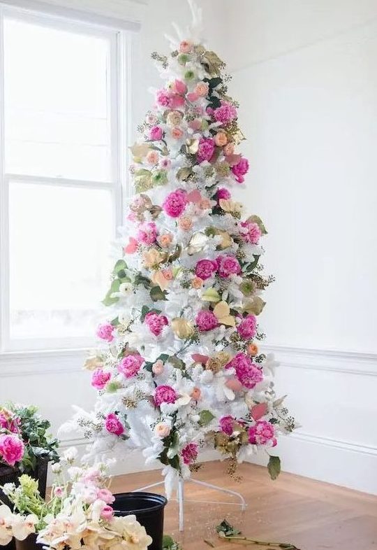 a romantic white Christmas tree decorated with hot pink and blush blooms, leaves and gilded foliage is super elegant