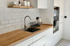 a simple white Scandi kitchen with sleek cabinets, butcherblock countertops and a white subway tile backsplash