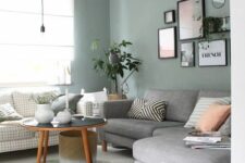 a small Scandinavian living room with pale green walls, a grey and printed sofa, a coffee table and a gallery wall