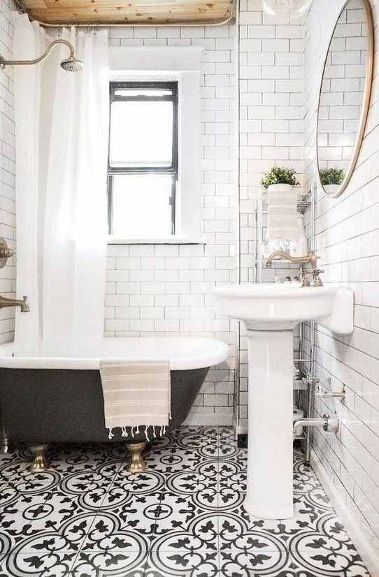 a small and bright bathroom with a mosaic floor, a wooden ceiling, a black clawfoot tub and a free-standing sink