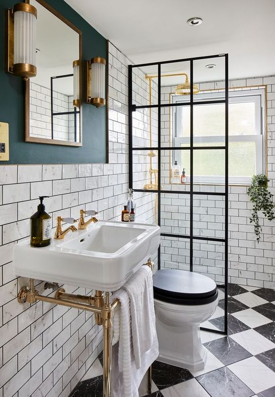 a stylish small bathroom with marble subway tiles, black and white marble ones on the floor, touches of gold and brass
