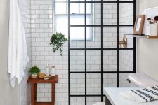 a vintage-inspired bathroom with white subway tiles and printed ones, a shower space with a screen, a black vanity and shelves