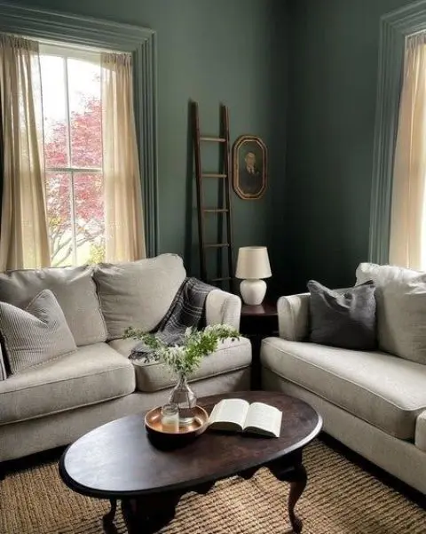 A vintage living room with green walls and a ceiling, grey sofas, a dark stained coffee table and some lovely decor