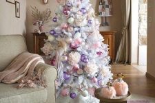 a white Christmas tree decorated with lilac, pink baubles and faux blooms looks very refined