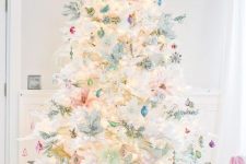 a white Christmas tree decorated with lots of various pastel ornaments, lights and an angel tree topper plus pastel gift boxes